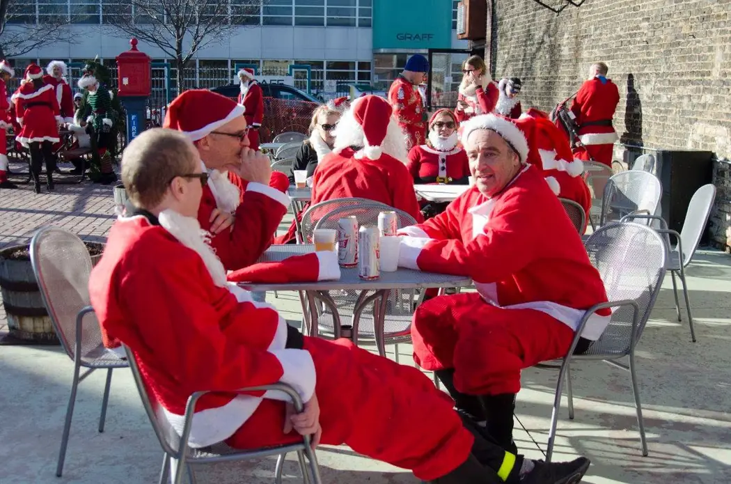 Santa-costumed riders gathering around outdoor tables during the 2015 Santa Rampage